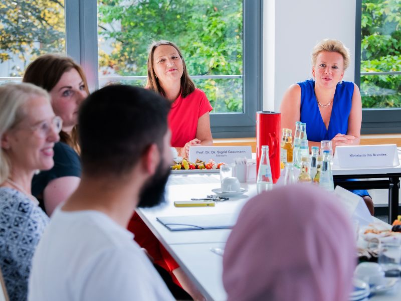 Gesprächssituation im Seminarraum mit Studierenden, Ministerin Ina Brandes und Rektorin Prof. Dr. Dr. Sigrid Graumann